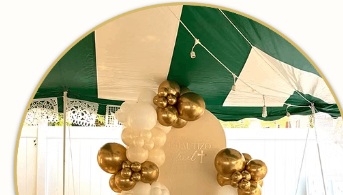 Detail of white and gold balloons around an outdoor celebration backdrop