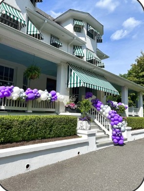 Purple and white balloon garland on a house porch