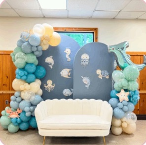 Under-the-sea baby shower setting with blue backdrops and a white sofa
