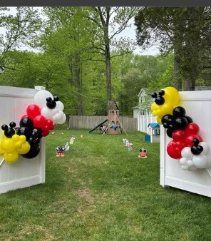 Black, red and yellow themed balloon columns in a backyard