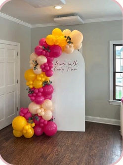 Pink, yellow and ivory balloons framing a personalized backdrop