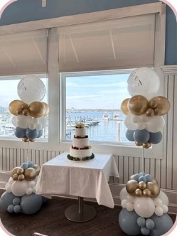 White, blue and gold balloon columns surrounding a cake table