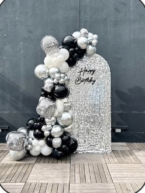 Silver and black balloon garland over a glitter birthday backdrop