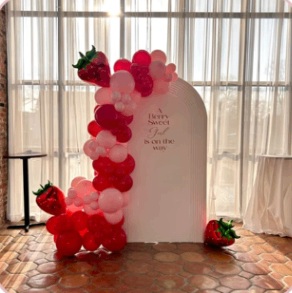 Red and pink strawberry-inspired baby shower balloon décor
