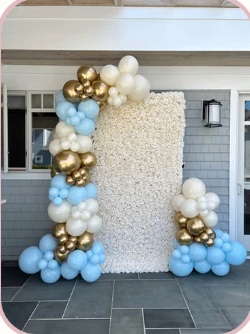 Blue, ivory and gold balloon installation with a white flower wall