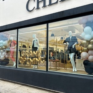 Black, gold and white balloons celebrating a boutique's grand opening window display
