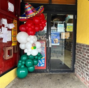 Red, white and green balloon garland with a festive sombrero on a storefront door