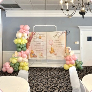 Pink, yellow and green balloon décor framing an open-book backdrop