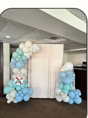 Soft blue and white balloon arch with draped curtains