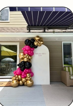 Black, gold and pink balloon arch on an outdoor patio