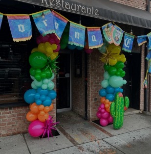 Colorful balloon columns with cactus accents beside a restaurant entrance