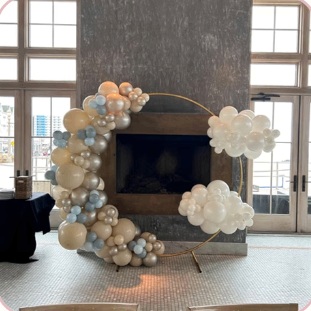 Neutral balloon garland around a circular frame beside a fireplace