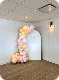 Soft peach and pink balloon garland on a white arched panel